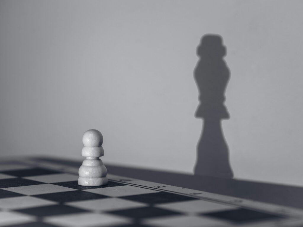 White chess pawn casting a shadow of a queen, symbolizing growth and transformation.